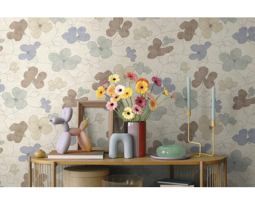 Vliesbehang met groot bloemmotief in lichte kleuren, gecombineerd met moderne decoratie op een sidetable.