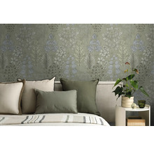 Vliesbehang met botanisch bladerpatroon in een slaapkamer achter een bed met groene en crèmekleurige kussens.