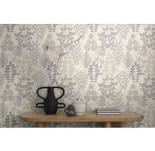 Modern vliesbehang met grafisch bladerpatroon in een lichte kamer achter een houten consoletafel met decoratieve vazen.