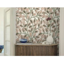 Vliesbehang met een bladerpatroon achter een houten dressoir met decoratie en een witte vaas in een lichte kamer.