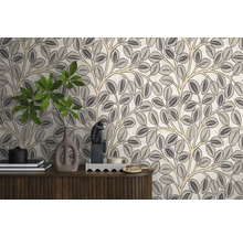 Vliesbehang met gestileerd bladeren- en takkenpatroon op een muur achter een houten dressoir met diverse decoratieve voorwerpen.