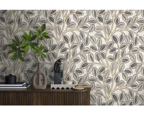 Vliesbehang met gestileerd bladeren- en takkenpatroon op een muur achter een houten dressoir met diverse decoratieve voorwerpen.