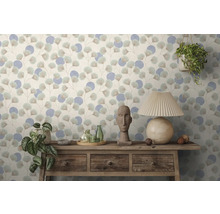 Behang met ginkgoblad- en cirkelpatroon achter een rustiek houten dressoir met stenen beeld, glazen flessen, planten en een tafellamp.