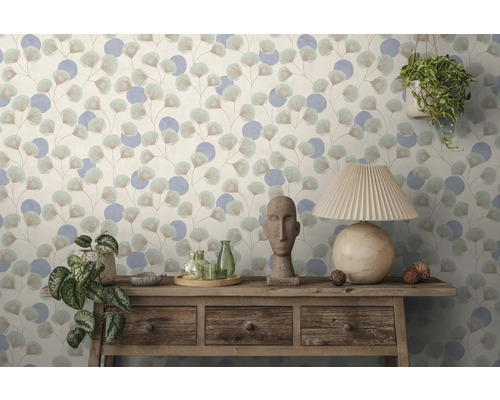 Behang met ginkgoblad- en cirkelpatroon achter een rustiek houten dressoir met stenen beeld, glazen flessen, planten en een tafellamp.