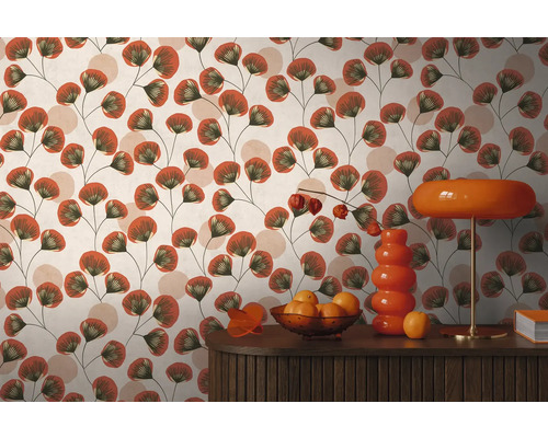 Behang met bloemenpatroon van waaiervormige bladeren op dunne stelen in een kamer met houten dressoir, vaas en tafellamp.