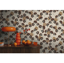 Vliesbehang met bladpatroon in bruin en beige achter een dressoir met oranje lamp en vaas in retrostijl.