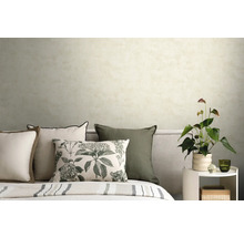 Slaapkamer met licht gestructureerd behang, sierkussens met bloemenprint en een bijzettafel met kamerplant.