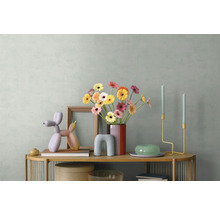 Moderne dressoirdecoratie met kleurrijke gerbera's in een vaas, een ballonhondsculptuur, houten lijst en minimalistische kandelaars.