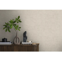 Vliesbehang in pleisterlook op een muur achter een houten dressoir met decoratie zoals een vaas met takken en een sculptuur.