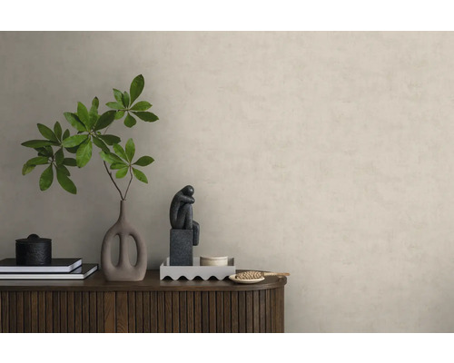 Vliesbehang in pleisterlook op een muur achter een houten dressoir met decoratie zoals een vaas met takken en een sculptuur.