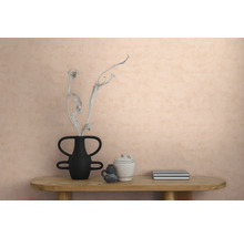 Vliesbehang met structuur op een muur in een modern interieur met een houten tafel, een vaas met een tak, keramiek en boeken.
