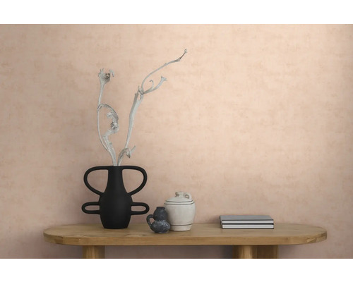 Vliesbehang met structuur op een muur in een modern interieur met een houten tafel, een vaas met een tak, keramiek en boeken.