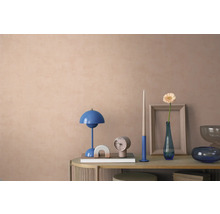Gedecoreerde console voor een muur met textuur, met een blauwe tafellamp, klok en vaas met bloem in een modern, georganiseerd interieur.