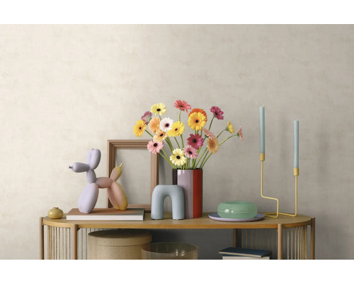 Modern interieur met houten dressoir, boeket gerbera's in een vaas, ballonhond-sculptuur, kandelaars en fotolijst voor een lichte wand.