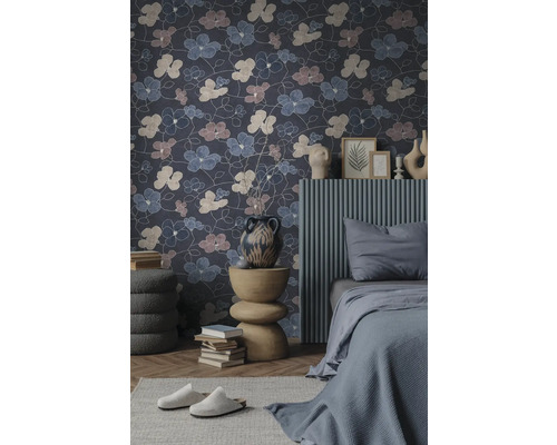 Vliesbehang met een groot bloemenpatroon in een modern ingerichte slaapkamer met een grijs bed en een decoratieve bijtafel.