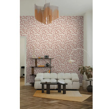 Vliesbehang met roze bladpatroon in een modern ingerichte woonkamer met een witte bank en een donkere salontafel.