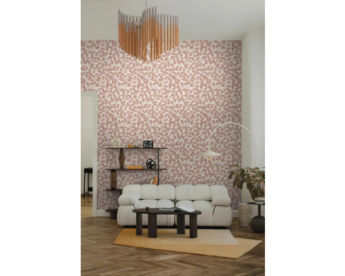 Vliesbehang met roze bladpatroon in een modern ingerichte woonkamer met een witte bank en een donkere salontafel.