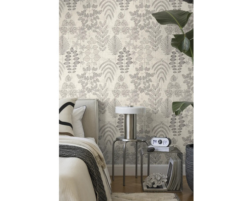 Vliesbehang met botanisch bladmotief in een lichte slaapkamer met bed, metalen tafeltjes en een grote kamerplant.