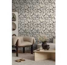 Moderne woonkamer met vliesbehang met botanisch patroon van bladeren in grijs en beige, lichte fauteuil, houten tafel en witte kast.