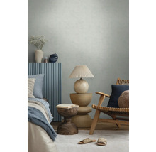 Moderne slaapkamer met gestructureerd behang, houten meubels, blauwe wandpanelen, decoratieve lamp en textiel in een lichte sfeer.