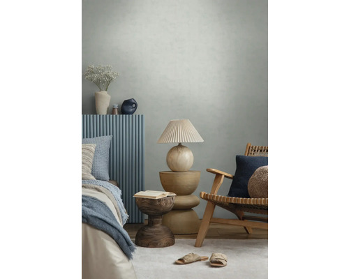 Moderne slaapkamer met gestructureerd behang, houten meubels, blauwe wandpanelen, decoratieve lamp en textiel in een lichte sfeer.