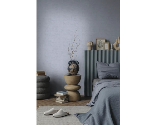 Moderne slaapkamer met lichtblauwe structuurwand, bed met grijs lattenhoofdbord en sculpturale houten bijzettafel.