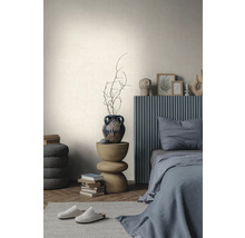 Lichte wand met textuur in een minimalistische slaapkamer met een grijs bed, houten bijzettafel en visgraatparket.