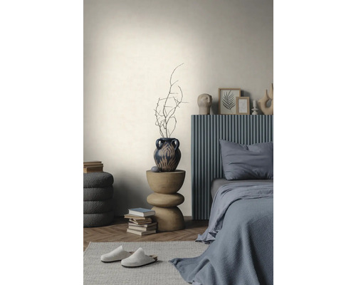 Lichte wand met textuur in een minimalistische slaapkamer met een grijs bed, houten bijzettafel en visgraatparket.
