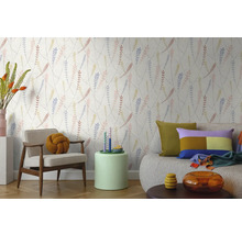 Vliesbehang met verfijnd bladerpatroon in een lichte woonkamer met een moderne fauteuil, bank en bijzettafel.