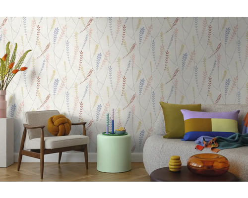 Vliesbehang met verfijnd bladerpatroon in een lichte woonkamer met een moderne fauteuil, bank en bijzettafel.