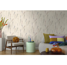 Vliesbehang met botanisch bladpatroon in een lichte woonkamer met fauteuil en bank.