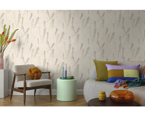 Vliesbehang met botanisch bladpatroon in een lichte woonkamer met fauteuil en bank.