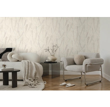 Moderne woonkamer met behang met botanisch patroon, witte bank, grijze fauteuil en visgraatvloer in een lichte, georganiseerde stijl.