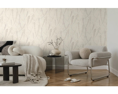 Moderne woonkamer met behang met botanisch patroon, witte bank, grijze fauteuil en visgraatvloer in een lichte, georganiseerde stijl.