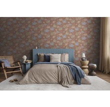 Vliesbehang met bloemenpatroon in een modern ingerichte slaapkamer met een gestoffeerd bed, houten fauteuil en licht textiel.