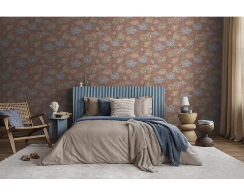 Vliesbehang met bloemenpatroon in een modern ingerichte slaapkamer met een gestoffeerd bed, houten fauteuil en licht textiel.