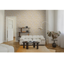 Woonkamer met geel behang met bladpatroon, witte modulaire bank, donkere salontafel en visgraatparket. Lichte en moderne sfeer.