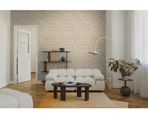 Woonkamer met geel behang met bladpatroon, witte modulaire bank, donkere salontafel en visgraatparket. Lichte en moderne sfeer.