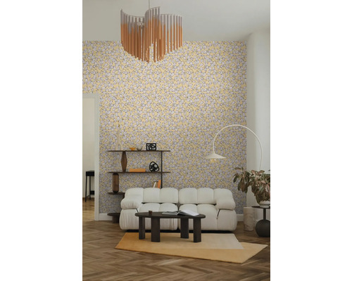 Lichte, georganiseerde woonkamer met behang met bladpatroon, witte modulaire bank, donkere salontafel, booglamp en houten rek.