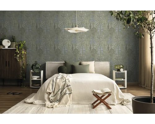 Slaapkamer met vliesbehang met botanisch bladpatroon in groen en blauw, licht bed, houten meubels en kamerplanten.