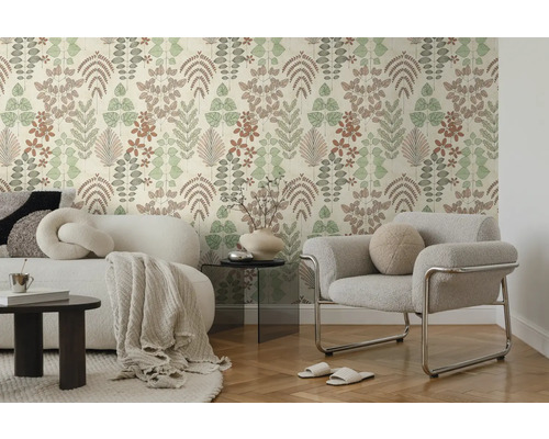 Moderne woonkamer met vliesbehang met bladmotief, witte bank met deken en grijze fauteuil op parketvloer.