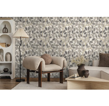 Vliesbehang met gestileerd bladerpatroon in een modern ingerichte woonkamer met fauteuil, vloerlamp en kast.