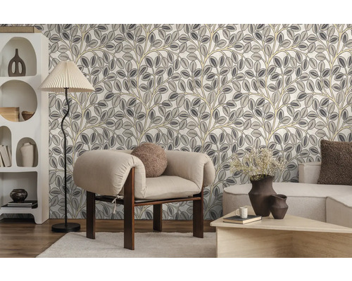 Vliesbehang met gestileerd bladerpatroon in een modern ingerichte woonkamer met fauteuil, vloerlamp en kast.
