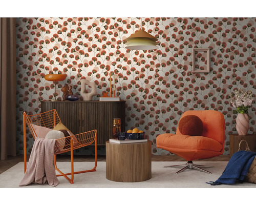 Moderne woonkamer met behang met bloemmotief, een donker dressoir, een oranje draadfauteuil en een gestoffeerde fauteuil op een licht tapijt.