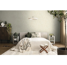 Licht ingerichte slaapkamer met bed, kussens met patroon, twee witte nachtkastjes, een hanglamp en gestructureerd behang op de muur.