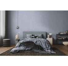 Moderne slaapkamer met blauwgrijze structuurwand, bed met geribbeld hoofdbord, parketvloer en donker vloerkleed.