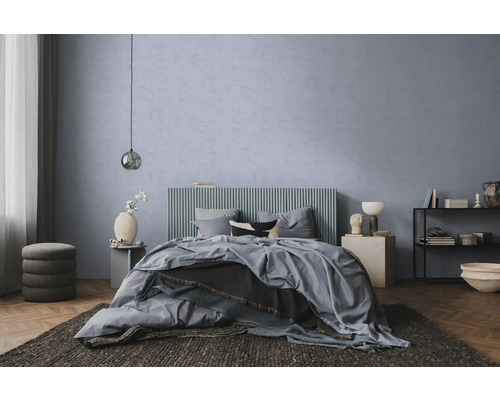 Moderne slaapkamer met blauwgrijze structuurwand, bed met geribbeld hoofdbord, parketvloer en donker vloerkleed.