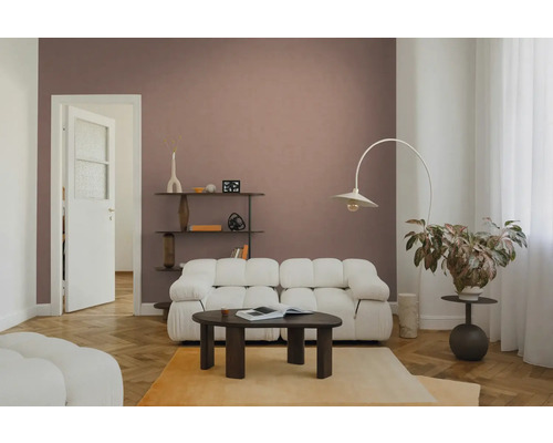 Moderne woonkamer met witte modulaire bank, donkerhouten salontafel en een booglamp voor een oudroze muur.