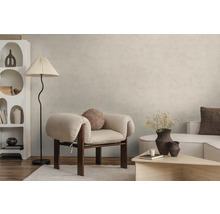Moderne woonkamer met lichtbeige muurverf in betonlook, lichte fauteuil, vloerlamp en witte designkast op houten vloer.