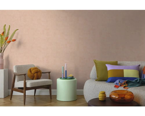 Moderne woonkamer met gestructureerde wandverf in perzikkleur, fauteuil, bank en kleurrijke decoratie.